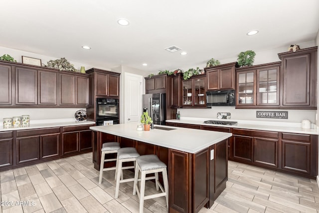 913 W Yosemite Dr, Chandler, AZ 85248 - kitchen with stainless steel appliances, light countertops, glass insert cabinets, a center island with sink, and a kitchen bar