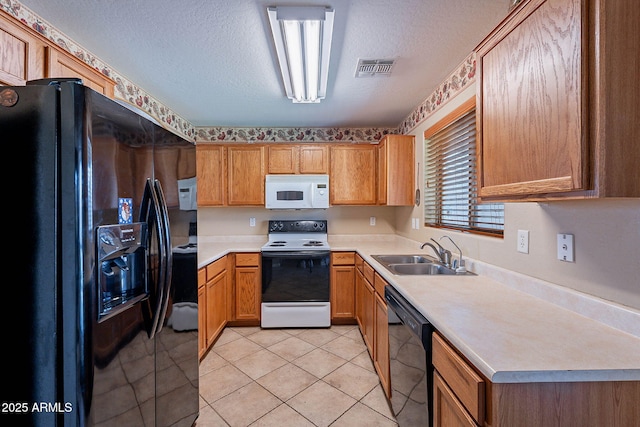 kitchen featuring sink, light tile patterned floors, black appliances, and a textured ceiling