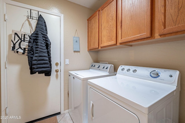 washroom featuring washing machine and dryer, light tile patterned floors, and cabinets