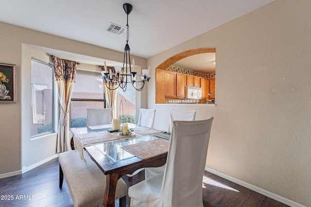 dining area with a notable chandelier and dark hardwood / wood-style floors