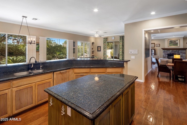 kitchen featuring dark hardwood / wood-style flooring, decorative light fixtures, a center island, and sink