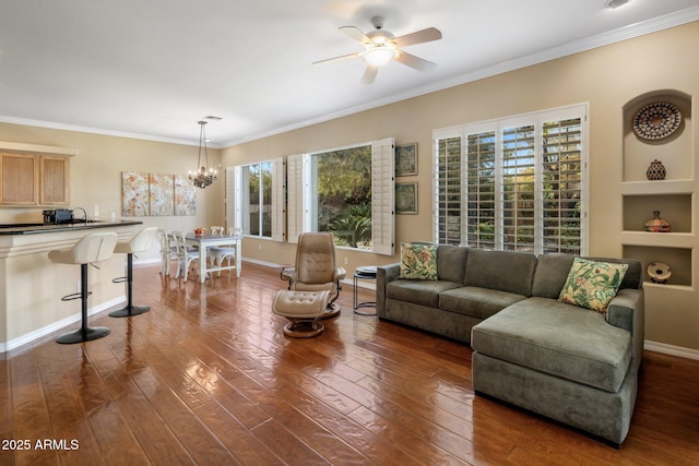 living room featuring dark hardwood / wood-style flooring, sink, ceiling fan with notable chandelier, and ornamental molding