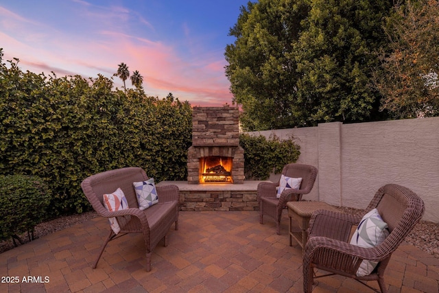 patio terrace at dusk featuring an outdoor stone fireplace