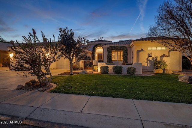 mediterranean / spanish house featuring a garage and a yard