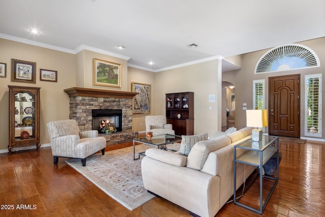 living room with crown molding, a stone fireplace, and dark hardwood / wood-style flooring