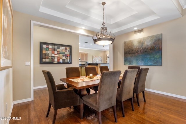 dining room featuring wood-type flooring and a tray ceiling