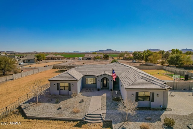 view of front of house with stucco siding, a mountain view, a tiled roof, and fence