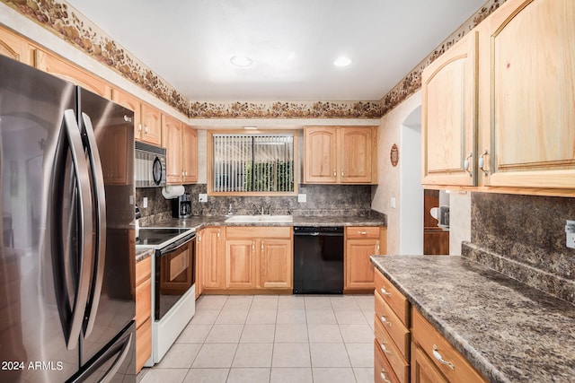 kitchen with appliances with stainless steel finishes, sink, light tile floors, dark stone counters, and tasteful backsplash