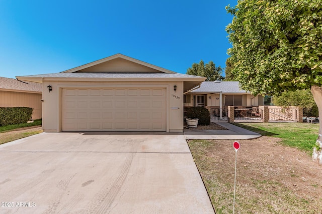 single story home featuring a garage, driveway, fence, and stucco siding