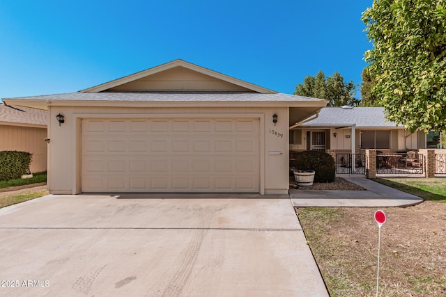 ranch-style house featuring driveway, an attached garage, and fence