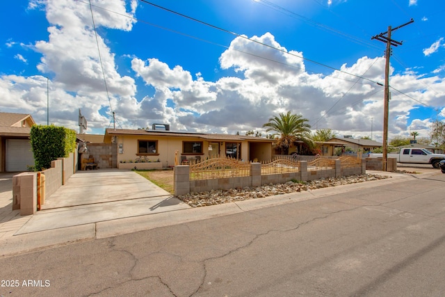 ranch-style home featuring a gate, driveway, solar panels, stucco siding, and a fenced front yard