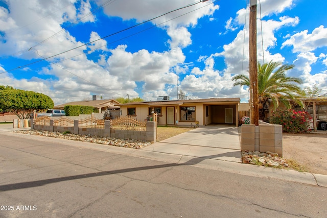 ranch-style house featuring a fenced front yard, a carport, and driveway