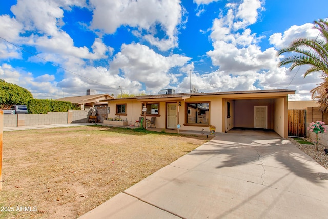 ranch-style home featuring concrete driveway, fence, a carport, and stucco siding