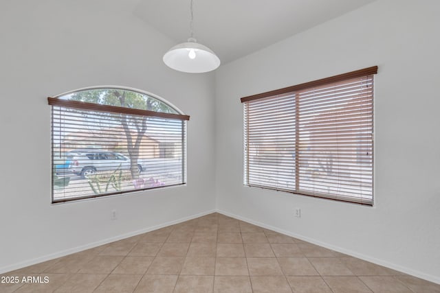 tiled spare room featuring lofted ceiling