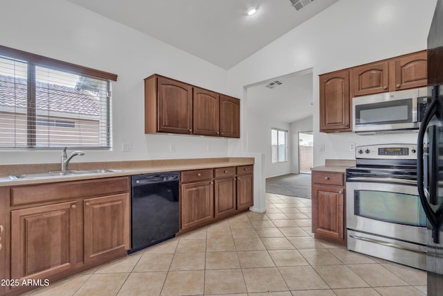 kitchen with sink, light tile patterned floors, black appliances, and high vaulted ceiling