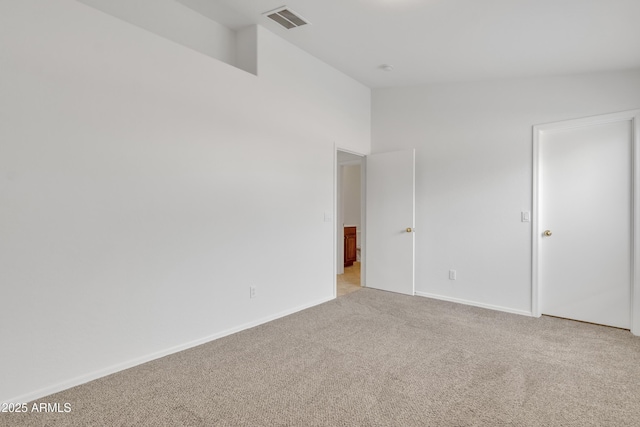 spare room featuring light carpet and lofted ceiling