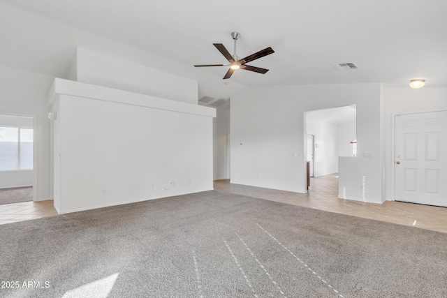 unfurnished living room with vaulted ceiling, light colored carpet, and ceiling fan