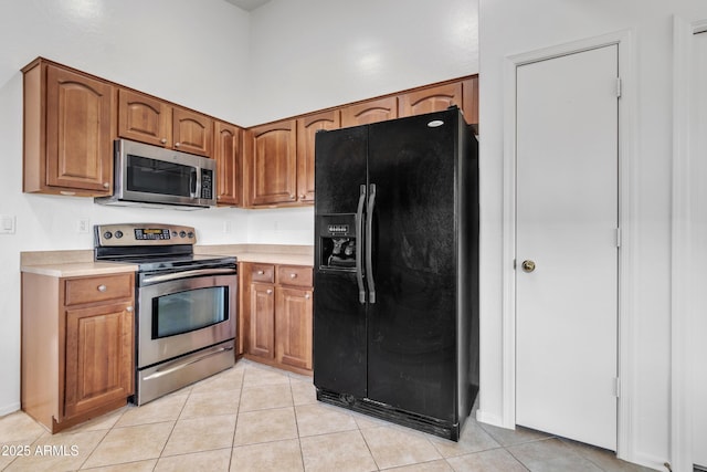 kitchen featuring light tile patterned floors, a towering ceiling, and appliances with stainless steel finishes