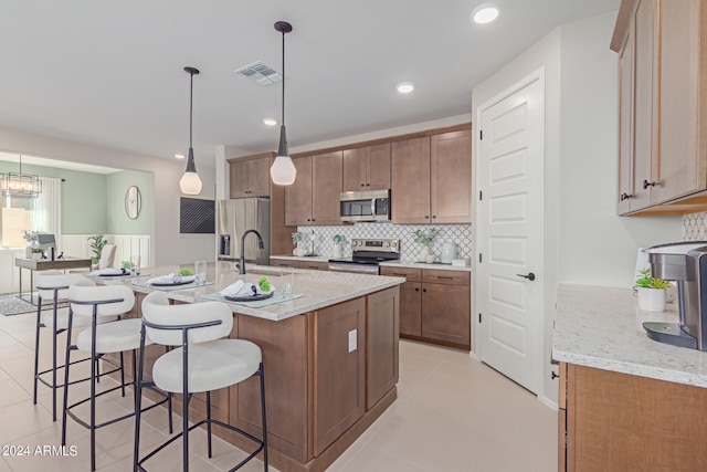 kitchen featuring tasteful backsplash, visible vents, a breakfast bar area, stainless steel appliances, and a sink