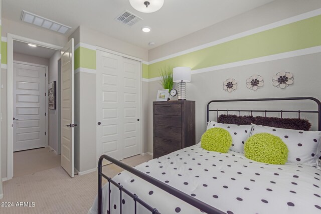 bedroom featuring a closet, visible vents, and light carpet