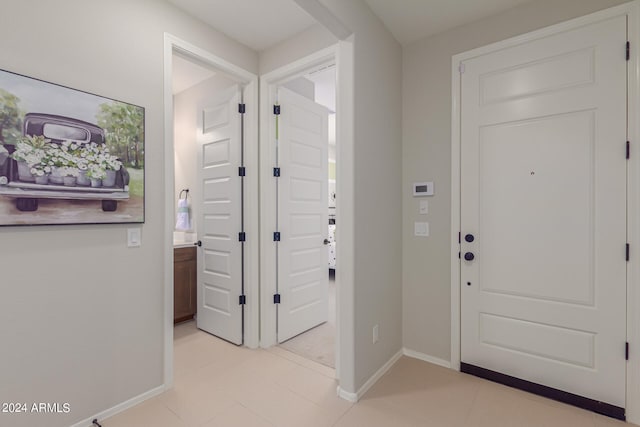 entryway with light tile patterned flooring and baseboards