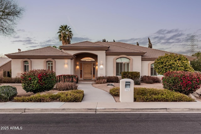 mediterranean / spanish home with a tile roof and stucco siding