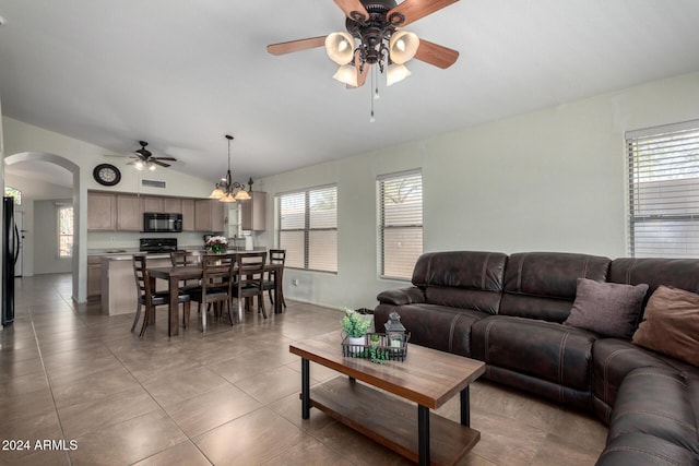 tiled living room featuring ceiling fan with notable chandelier and lofted ceiling