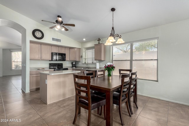 tiled dining space featuring ceiling fan with notable chandelier, vaulted ceiling, and sink