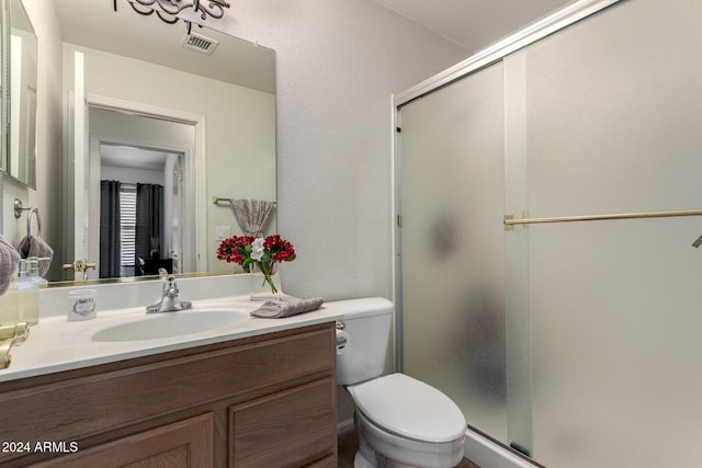 bathroom featuring vanity, a shower with shower door, and toilet