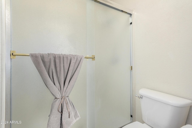 bathroom with a shower with shower door and toilet