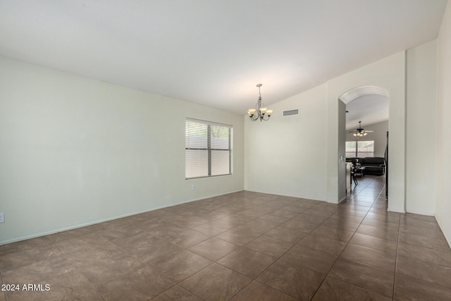 unfurnished room featuring ceiling fan with notable chandelier, dark tile patterned flooring, and lofted ceiling