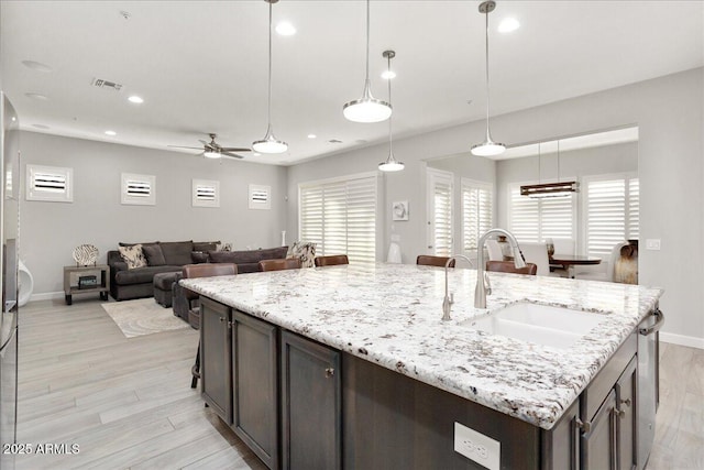 29344 N 132nd Ln, Peoria, AZ 85383 - kitchen featuring a sink, light wood-style floors, a ceiling fan, baseboards, and dark brown cabinetry