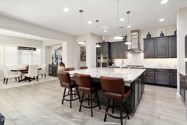 29344 N 132nd Ln, Peoria, AZ 85383 - kitchen featuring wall chimney range hood, double oven, tasteful backsplash, recessed lighting, and light stone counters