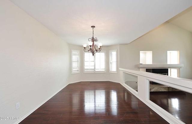 unfurnished dining area featuring a chandelier, hardwood / wood-style flooring, and baseboards
