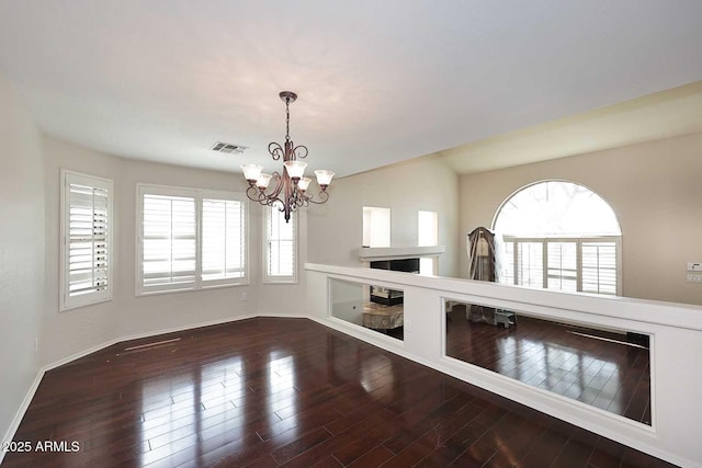 unfurnished dining area with a chandelier, wood finished floors, baseboards, and a fireplace