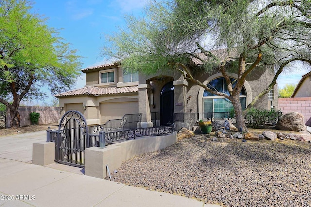 mediterranean / spanish-style home with a fenced front yard, stucco siding, a tile roof, and a garage