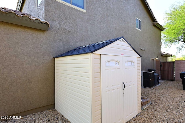 view of shed with central AC unit and fence