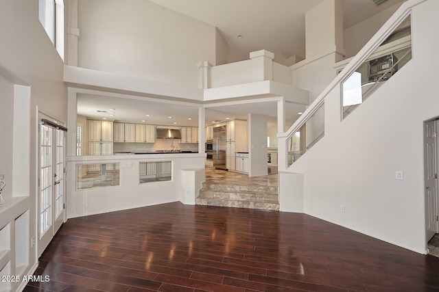 unfurnished living room featuring wood finished floors, a high ceiling, and french doors