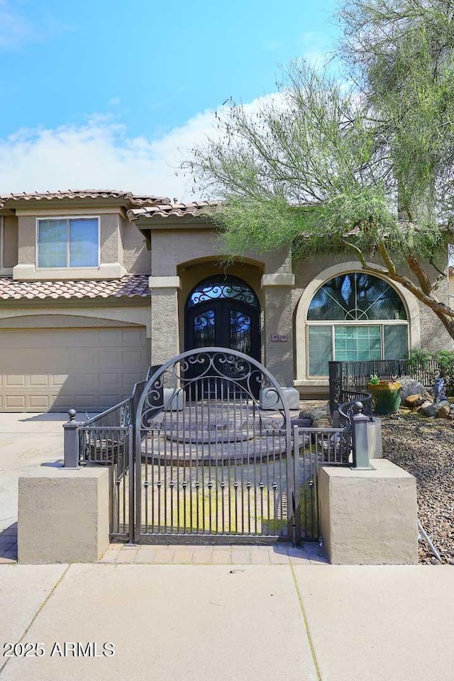 view of front of property featuring stucco siding, a fenced front yard, a gate, and driveway