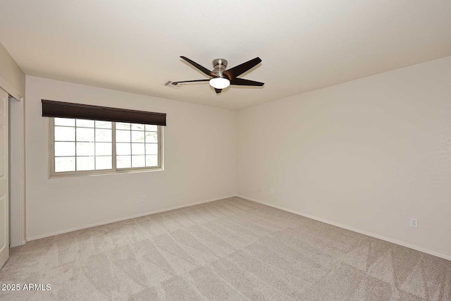 empty room with light colored carpet, a ceiling fan, and baseboards