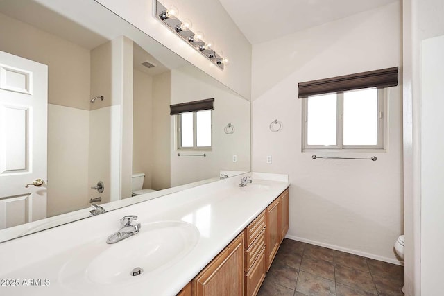 full bath featuring toilet, baseboards, double vanity, and a shower