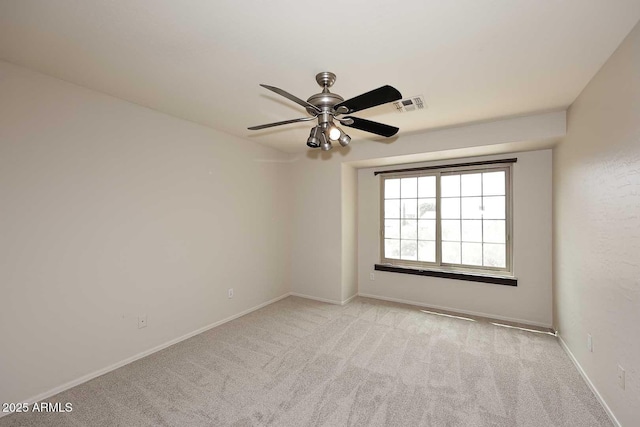 spare room featuring light carpet, a ceiling fan, and baseboards