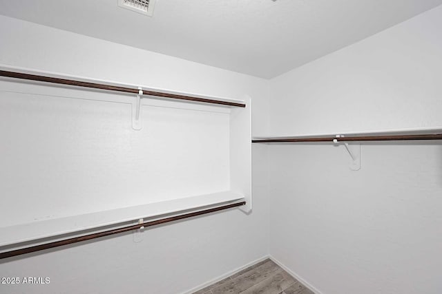 walk in closet with light wood finished floors