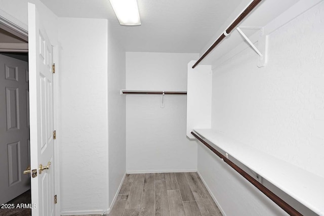 walk in closet with light wood-style floors