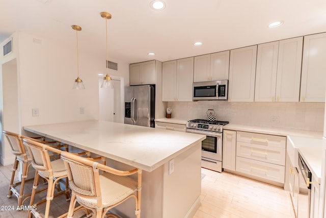 kitchen featuring pendant lighting, a kitchen breakfast bar, tasteful backsplash, kitchen peninsula, and stainless steel appliances