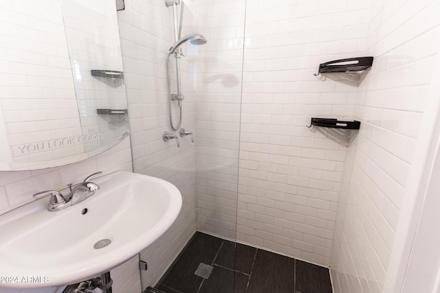 bathroom featuring a tile shower, backsplash, and sink