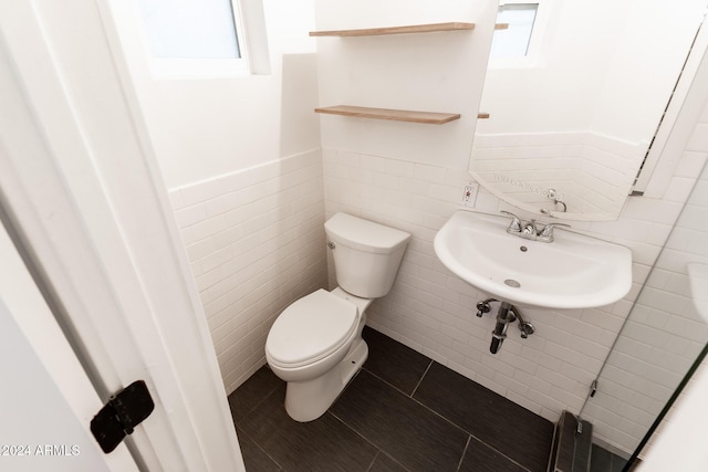 bathroom featuring tile patterned flooring, toilet, tile walls, and sink