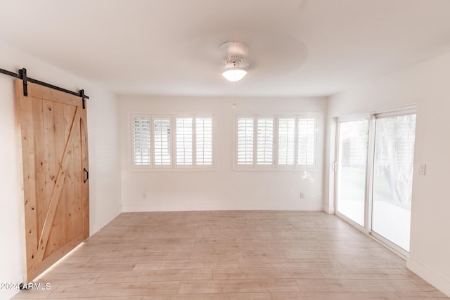 spare room featuring a barn door and light wood-type flooring