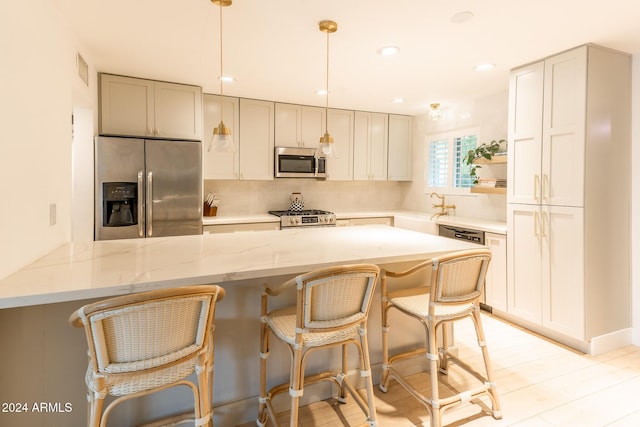 kitchen featuring light stone countertops, sink, a kitchen breakfast bar, pendant lighting, and appliances with stainless steel finishes