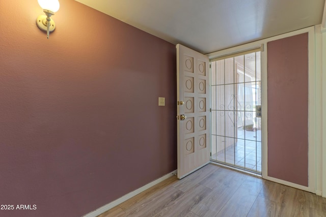 foyer with light wood-style floors, baseboards, and a wall of windows